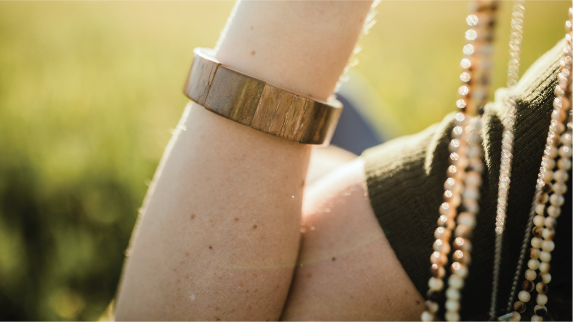 woman wearing an organic bracelet while holding up beaded necklaces.